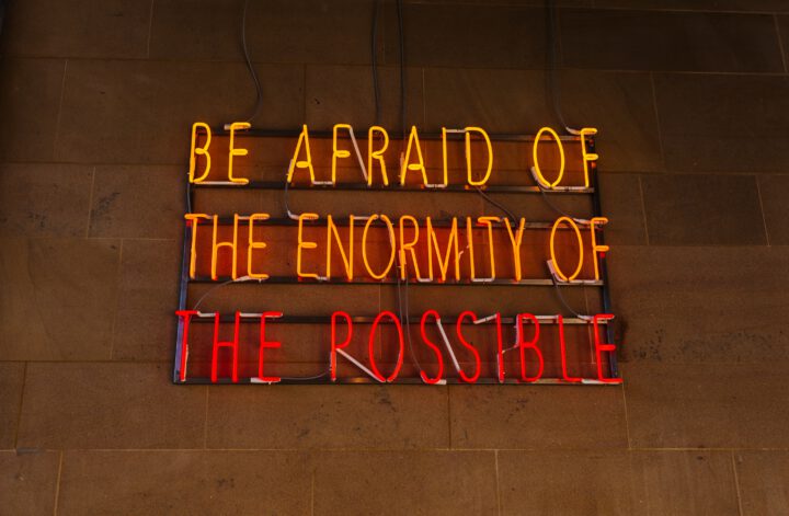 Glowing sign saying "Be afraid of the enormity of the possible"